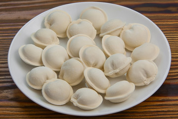 Raw frozen dumplings on  plate on table