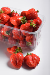 fresh organic strawberries in a plastic box on a white background. delivery of organic products. packaging of organic strawberries.