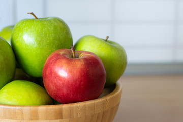 Wooden bowl with green apples and one red Apple close-up