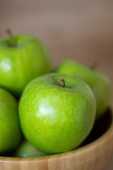 Green apples in a wooden bowl close-up. One green Apple close-up.