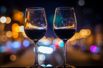 Two glasses of wine standing on the bridge with background of night city traffic lights.