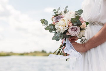 Bridal bouquet. Beautiful wedding pink and white flowers in hands of the bride. Close up outdoor...