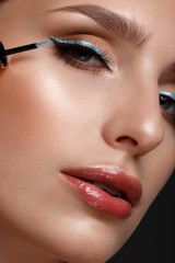 Beautiful girl with sexy lips and classic makeup with cosmetic blue eyeliner in hand. Beauty face.