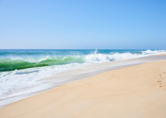 Fototapeta na wymiar atlantic green waves crashing on the beach at north beach, Nazaré