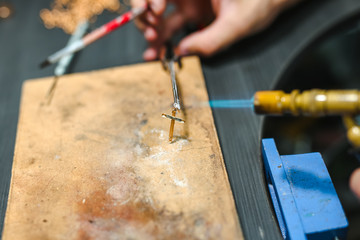 Master goldsmith while working  jewelry of gold cross on the of work table.