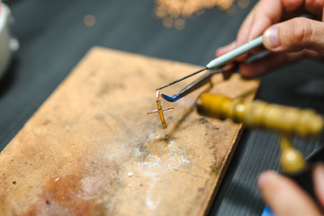 Master goldsmith while working  jewelry of gold cross on the of work table.