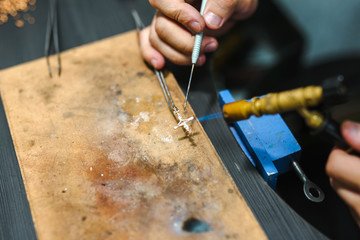 Master goldsmith while working  jewelry of gold cross on the of work table.