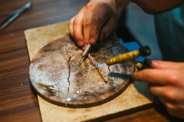 Master goldsmith while working on jewelry on the of work table.