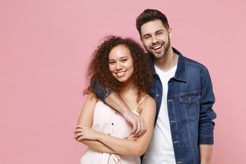 Smiling young couple two friends european guy african american girl in casual clothes isolated on pastel pink background. People lifestyle concept. Mock up copy space. Hugging, holding hands crossed.