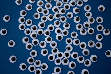 googly toy eyes on classic blue background. concept of personal data security, surveillance, espionage. top view