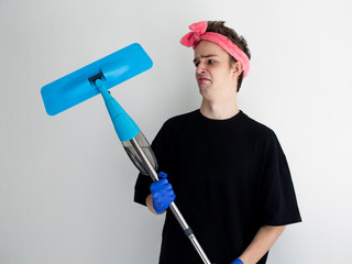 funny young man in a female hair band with a mop, housework, concept