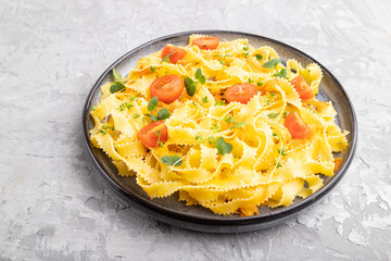 Reginelle pasta with tomato, eggs and microgreen sprouts on a gray concrete background. Side view.