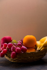 Apples, oranges, grapes, bananas in a basket.