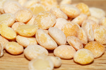 Raw split peas of yellow variety on the wooden surface and scattered beside, close-up in selective focus. Vegan food, stock photo