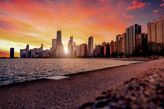 A view of downtown Chicago from North Avenue Beach as the sun sets behind the tall skyline buildings of the windy city.