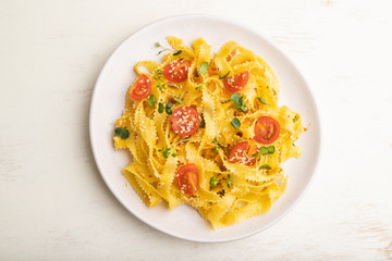Reginelle pasta with tomato, eggs, sesame and microgreen sprouts on a white wooden background. Top view, close up.