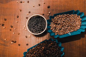 Closeup black coffee in paper cup and coffee beans spilled out the paper bag