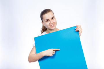 Naklejka premium A girl in a white T-shirt holds in her hands a blue blank large sheet of banner.