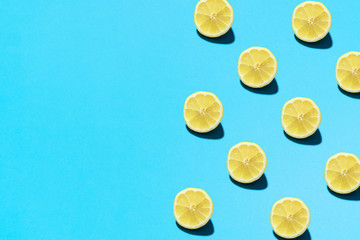 Summer abstract trendy fresh concept. Lemon pattern on bright light blue background, copy space. Minimal flat lay food texture.