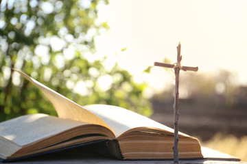 The Bible on the background of the cross and life-giving light