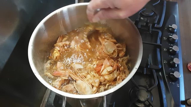 Preparation of bisque sauce. Tomato paste is added to the broth with prawns and mixed