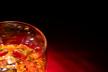 A glass of whiskey on the rocks on the red table. The view from the top