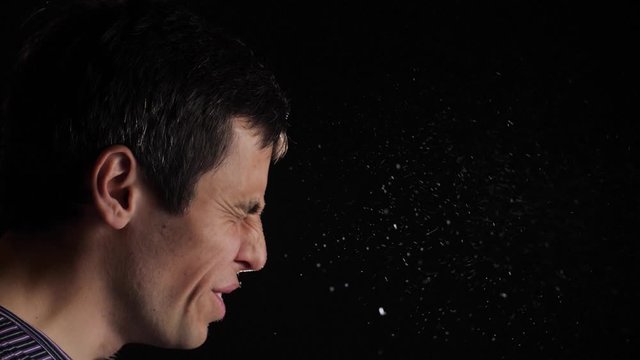 Man sneezes and spreads particles of saliva through the air