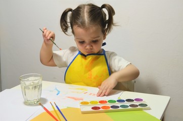 The girl draws watercolors with her fingers. The child is moving