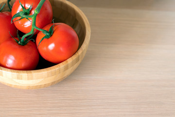red tomatoes from a wooden bowl on the table top view