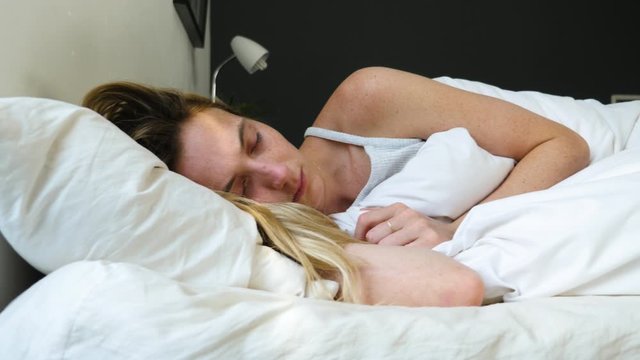 Portrait Of Beautiful Female Resting On Comfortable Bed With Pillows In White Bedding In Light Bedroom In Morning