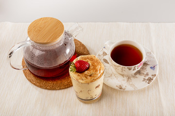 Tiramisu in a glass Cup, a Cup of tea and a glass teapot