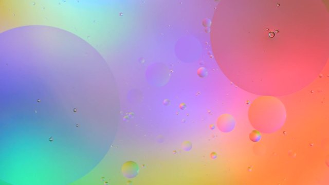 Top view movement of bubbles in the liquid. Oil surface multicolored background. Fantastic structure of colorful bubbles. Colorful artistic image of oil drop floating on the water