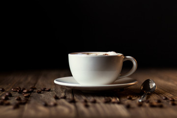 a Cup of coffee with milk and coffee beans on a dark wooden background. selective focus