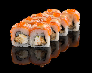 Sushi roll with salmon, cheese, eel, sauce and caviar isolated on black background with reflection