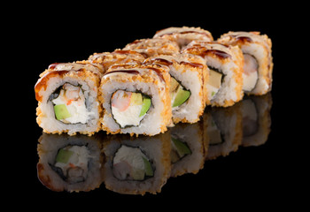 Sushi roll with shrimp, avocado, cheese, omelet breading isolated on black background with reflection