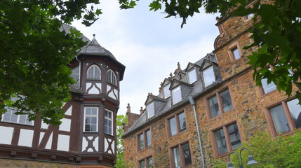 Von Bäumen umrahmte Fassade des Neuen Schlosses mit Fachwerk-Ecktürmchen 