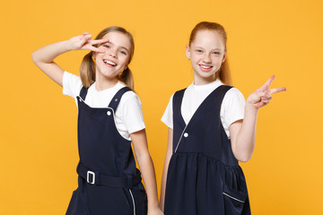 Two young little girls 12-13 years old in white t-shirt blue school uniform dresses isolated on...