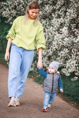 Fototapeta premium A mother plays and talks with a child against the background of a flowering tree