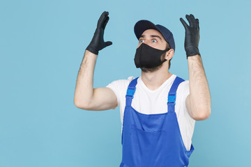 Fototapeta premium Delivery man in cap t-shirt coveralls uniform sterile face mask gloves isolated on blue background studio. Guy employee courier Service quarantine pandemic coronavirus virus covid-19 2019-ncov concept