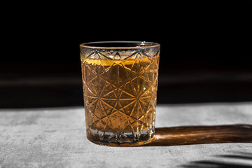 Glass of summer iced drink in harsh light with shadow