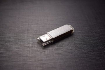 a gray flash drive lies on a dark table.