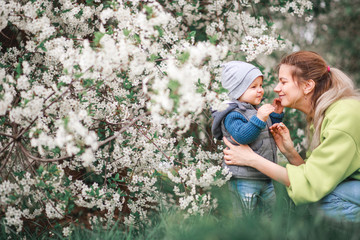 A mother plays and talks with a child against the background of a flowering tree