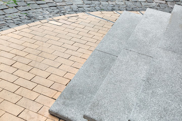 Granite stone steps descent to the pedestrian sidewalk of the old city from stone tiles, close-up.