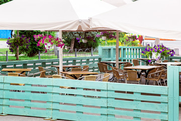 a free wooden table with a wicker chair of an outdoor cafe under an umbrella with hanging...