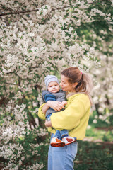Fototapeta premium happy mother and son play against the background of a flowering tree. Spring, mother's day.