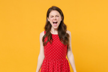 Crazy young brunette woman girl in red summer dress posing isolated on yellow background studio portrait. People sincere emotions lifestyle concept. Mock up copy space. Keeping eyes closed, screaming.