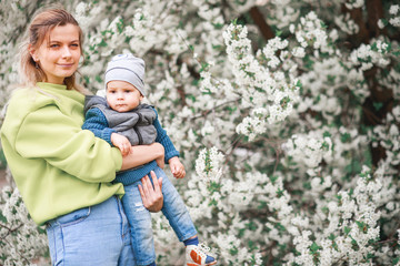 Fototapeta na wymiar happy mother and son play against the background of a flowering tree. Spring, mother's day.