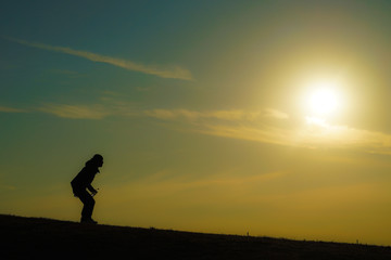 夕暮れの丘に立つ男性のシルエット