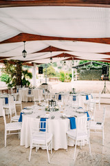 Wedding dinner table reception. Round banquet table with white tablecloth and white Chiavari chairs. Wedding under the tent. 