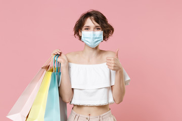 Smiling young woman girl in summer clothes sterile face mask hold package bag with purchases...